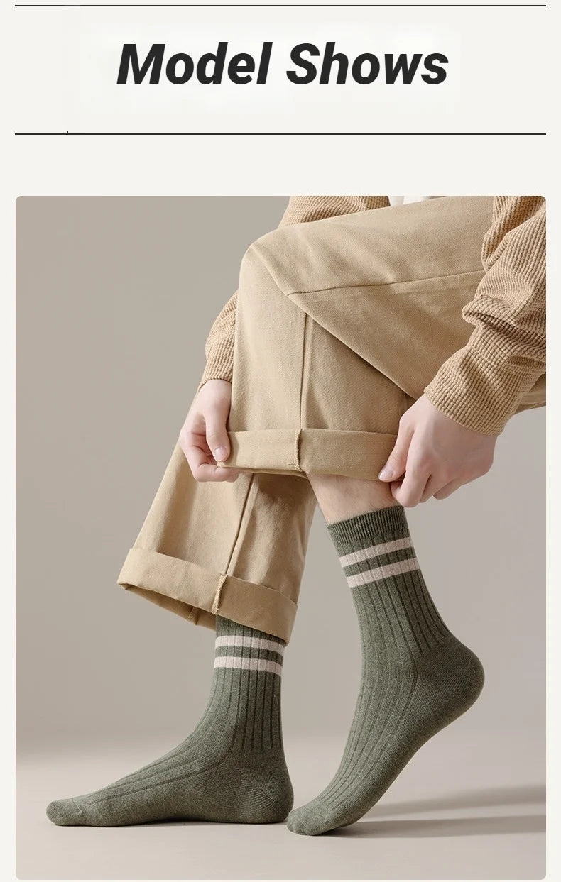 A close-up of a person wearing beige trousers and olive green striped socks.