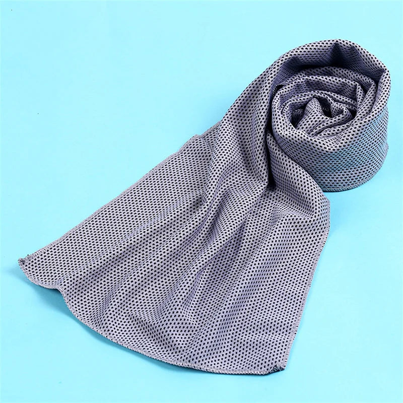 A gray microfiber cooling towel is rolled up on a light blue background.
