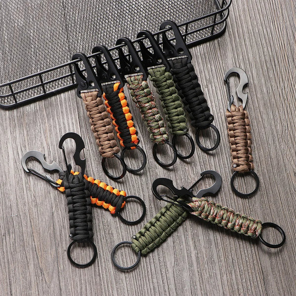A collection of multi-tool keychains in various camouflage and earth tones hanging from a black wire grid.