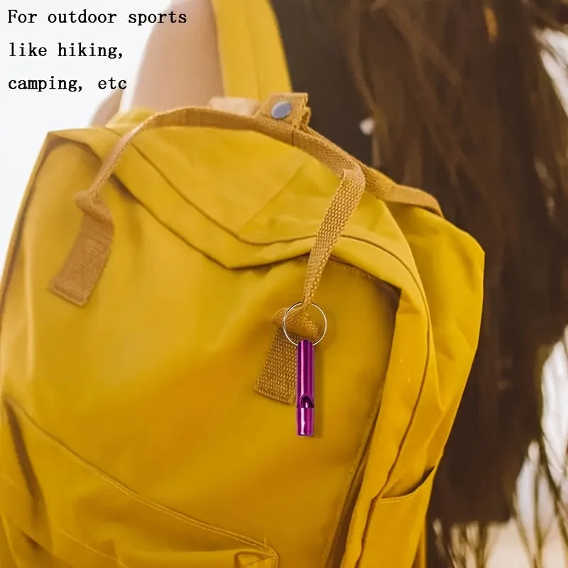 A yellow backpack with a purple whistle keychain attached to the strap.