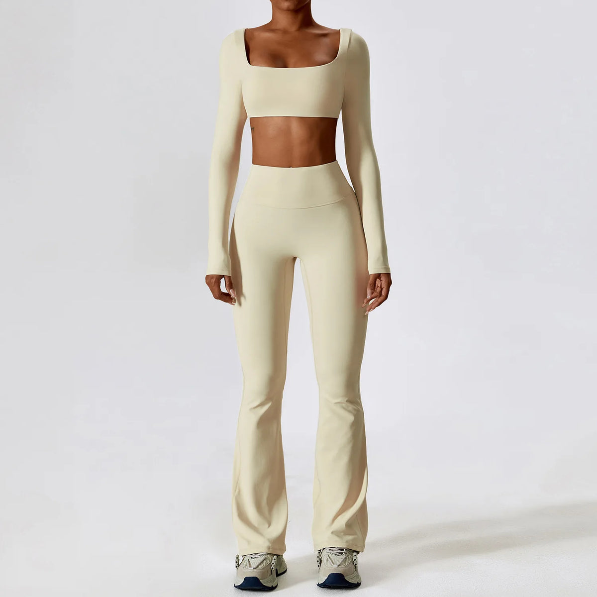 A woman wearing a beige women's performance tracksuit set consisting of a cropped top and matching full-length pants.