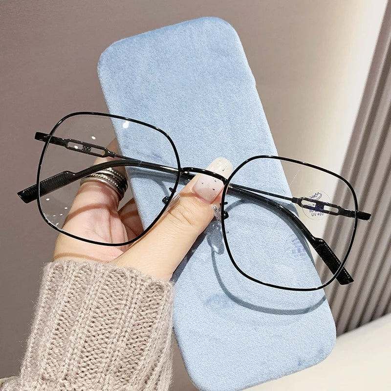 A pair of black anti-blue light reading glasses resting on a light blue cloth.