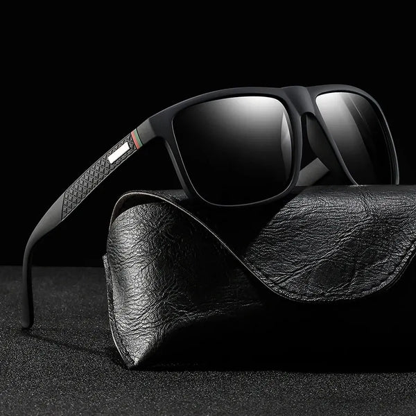 Black classic square designer sunglasses resting on a black leather strap.