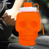 An orange skull-shaped leakproof sports water bottle with a clear cap and orange straw is held by a hand.