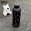 Taza de viaje de acero inoxidable aislada negra con patrones de mariposa rosa, junto a un perro blanco y esponjoso