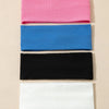 Un paquete de cuatro bandas elásticas para el cabello en rosa, azul, negro y blanco apiladas verticalmente.
