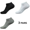 Tres pares de calcetines deportivos de algodón para el tobillo en negro, gris claro y gris medio.