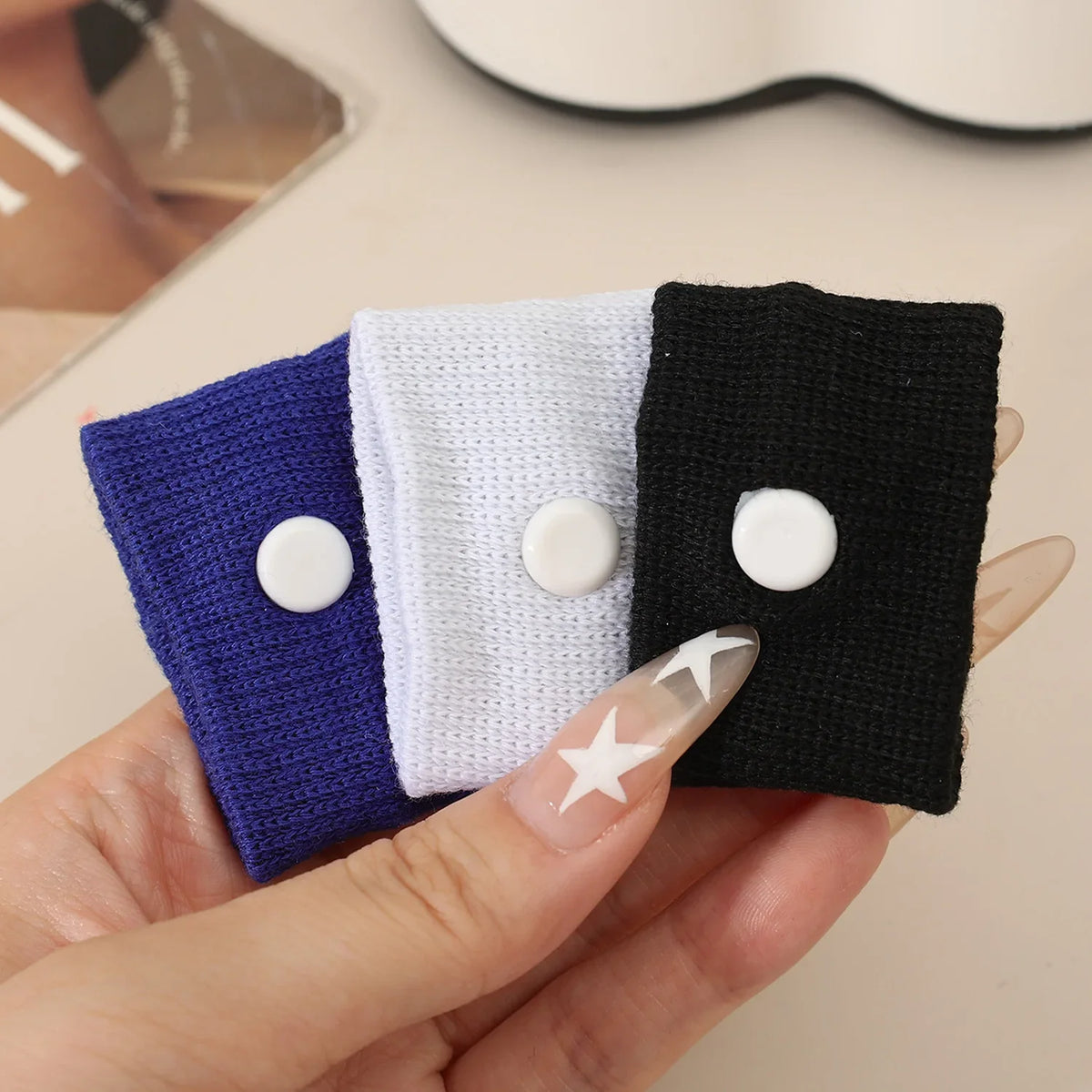 A hand holds three colored anti-nausea wristbands: purple, white, and black.
