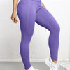 A woman wearing purple high-waisted sports leggings and white sneakers.