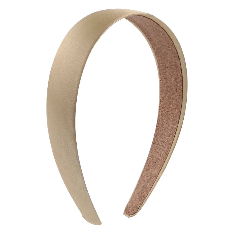 A close-up view of a solid satin hair band in a nude or blush pink color.