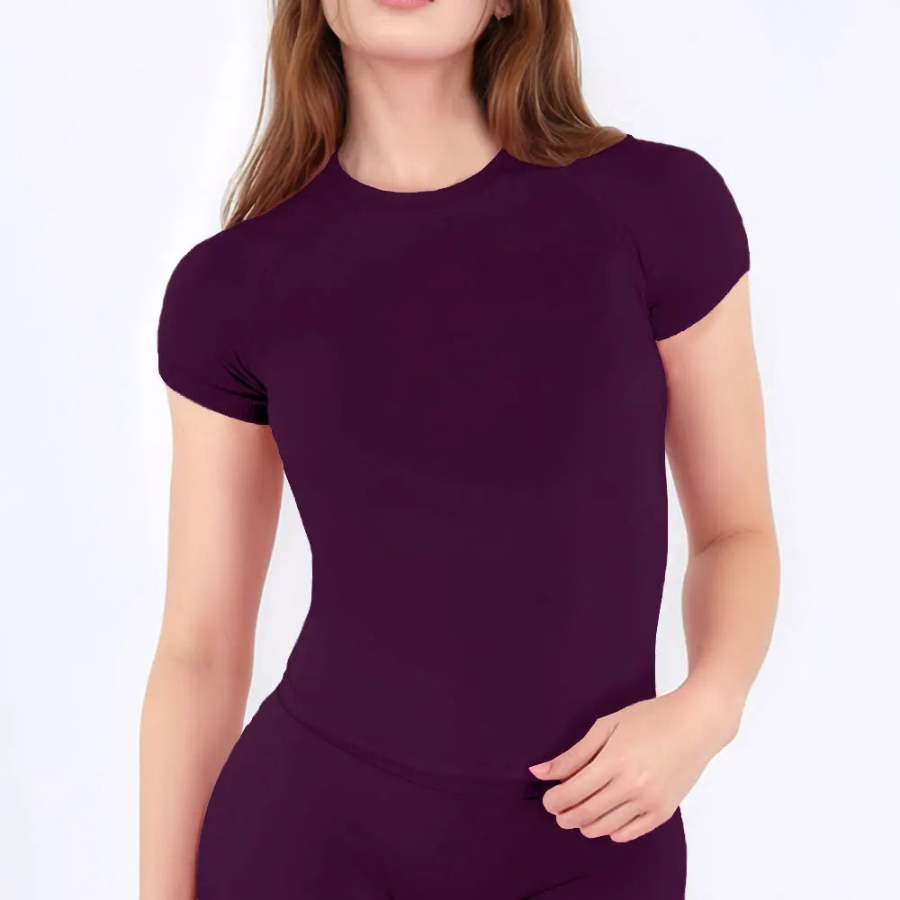 A woman wearing a deep purple performance fitness short sleeve top.