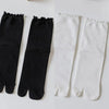 A pair of black and white knit crew socks with ruffle cuffs displayed side by side.
