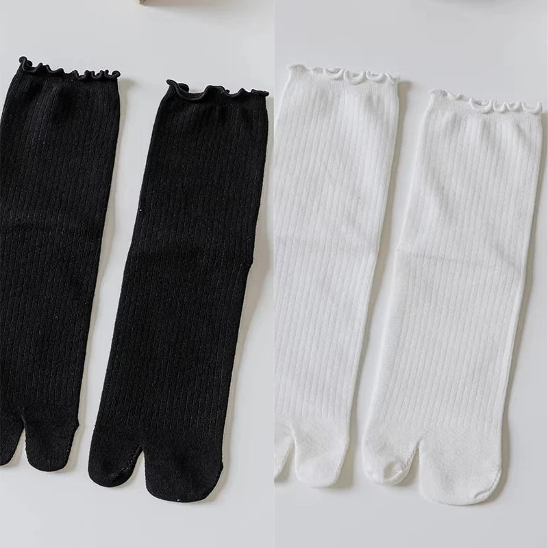 A pair of black and white knit crew socks with ruffle cuffs displayed side by side.
