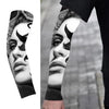 Close-up of a hand wearing black ice silk sun protection arm sleeves with intricate black and white facial designs.