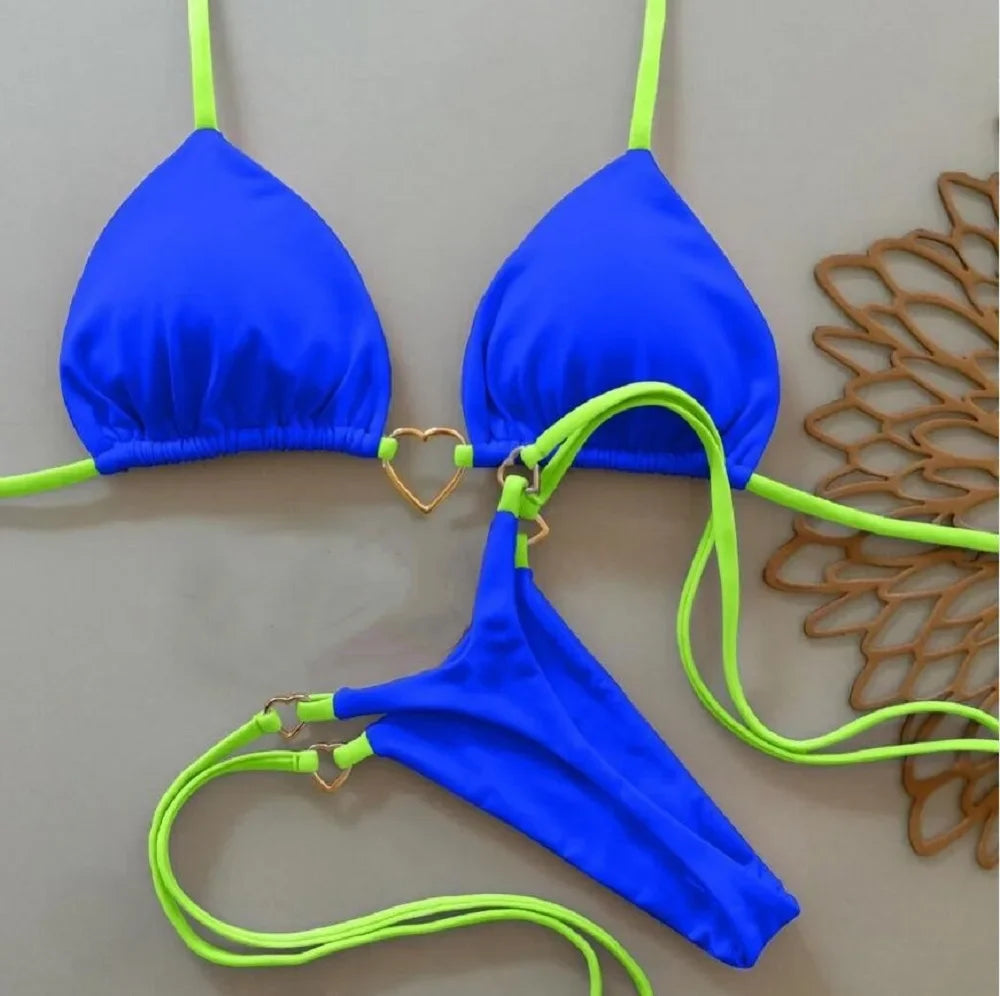 A bright blue halter bikini set with neon green straps laid out on a gray surface.