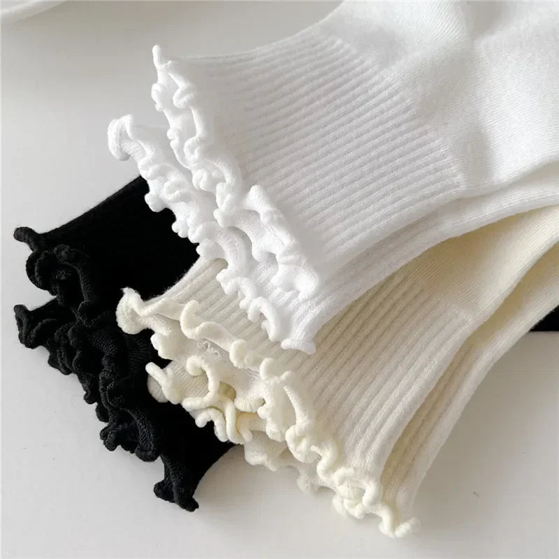 A stack of white and cream cotton ruffle ankle socks with black accents.