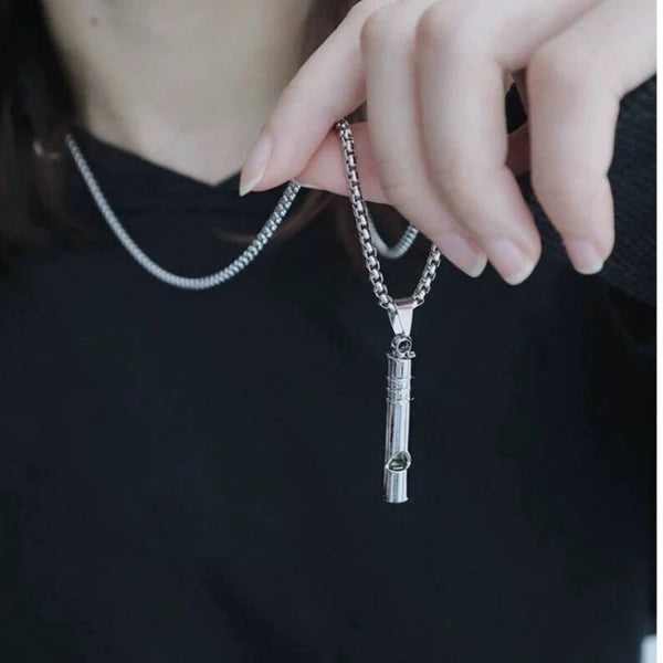 A hand wearing a silver chain necklace with a whistle pendant against a black shirt.