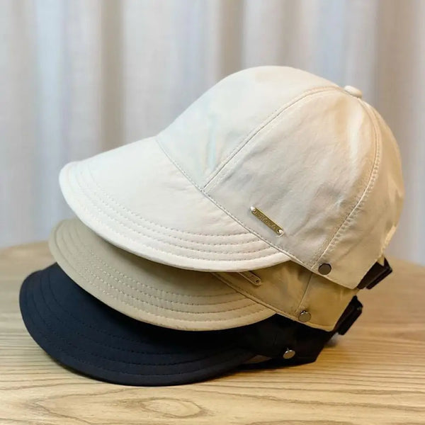 A beige wide brim UV protection baseball cap is shown stacked on a wooden surface.