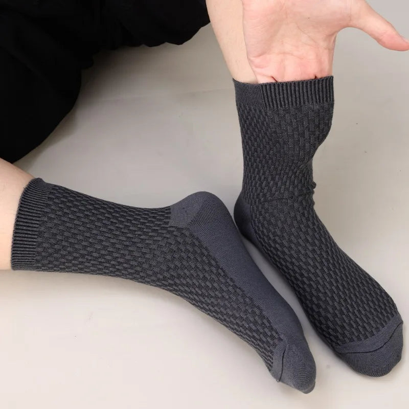 A pair of dark gray bamboo fibre anti-odor socks being held by a hand.