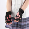Black plush cat claw mittens with pink pads worn on a person's hand against a plaid skirt.