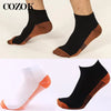 Une paire de chaussettes de compression en fibre de cuivre noir et orange, vue de profil.