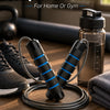 A black adjustable weighted speed jump rope coiled on a wooden surface next to athletic shoes and a water bottle.