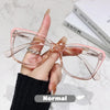 Eine Hand hält eine rosa photochromische multifokale Brille vor einem weißen Marmorhintergrund.