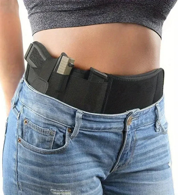 A black tactical outdoor belt is worn around the waist of a person wearing blue jeans.
