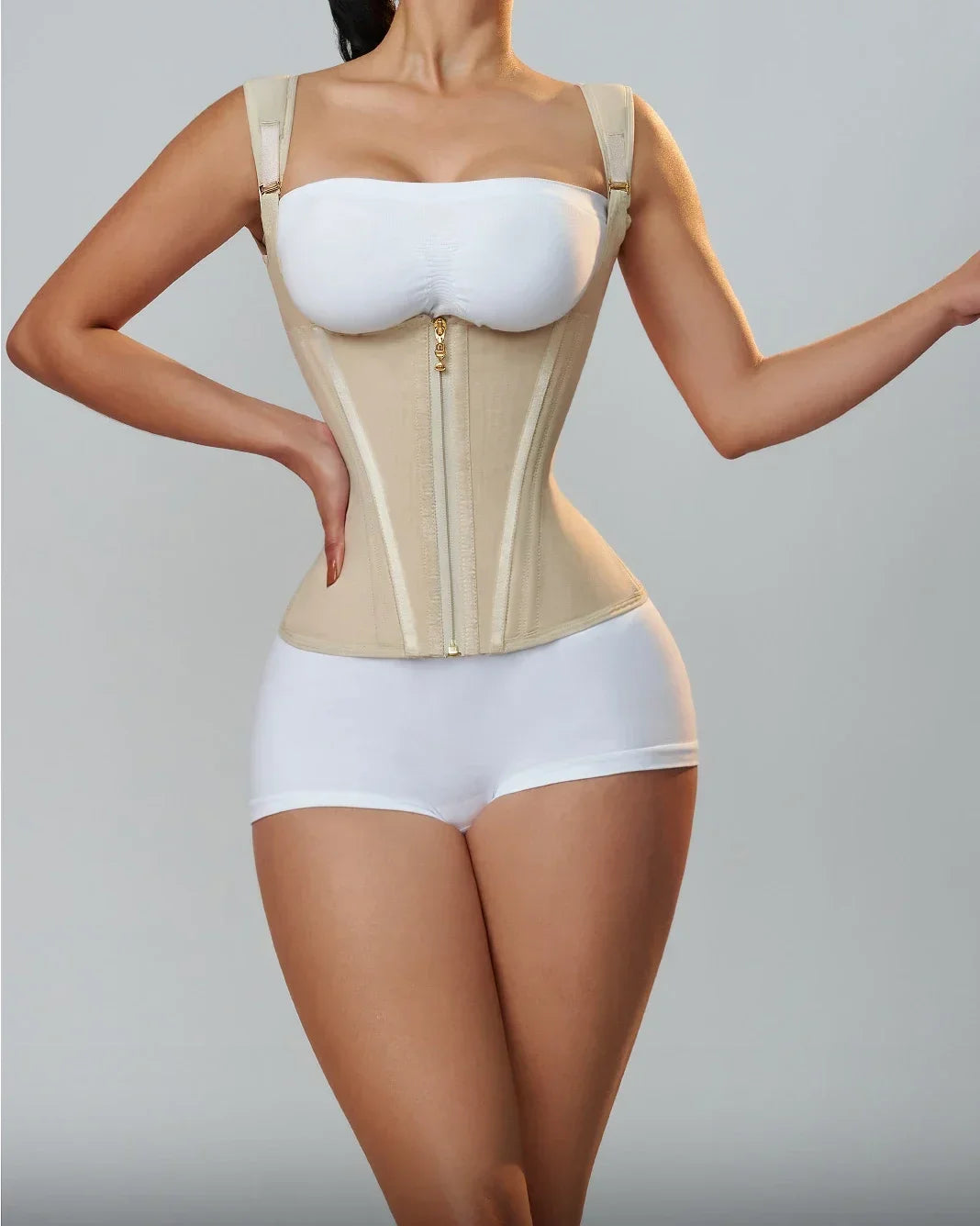 A woman models a beige adjustable body shaper corset vest top and matching white briefs.