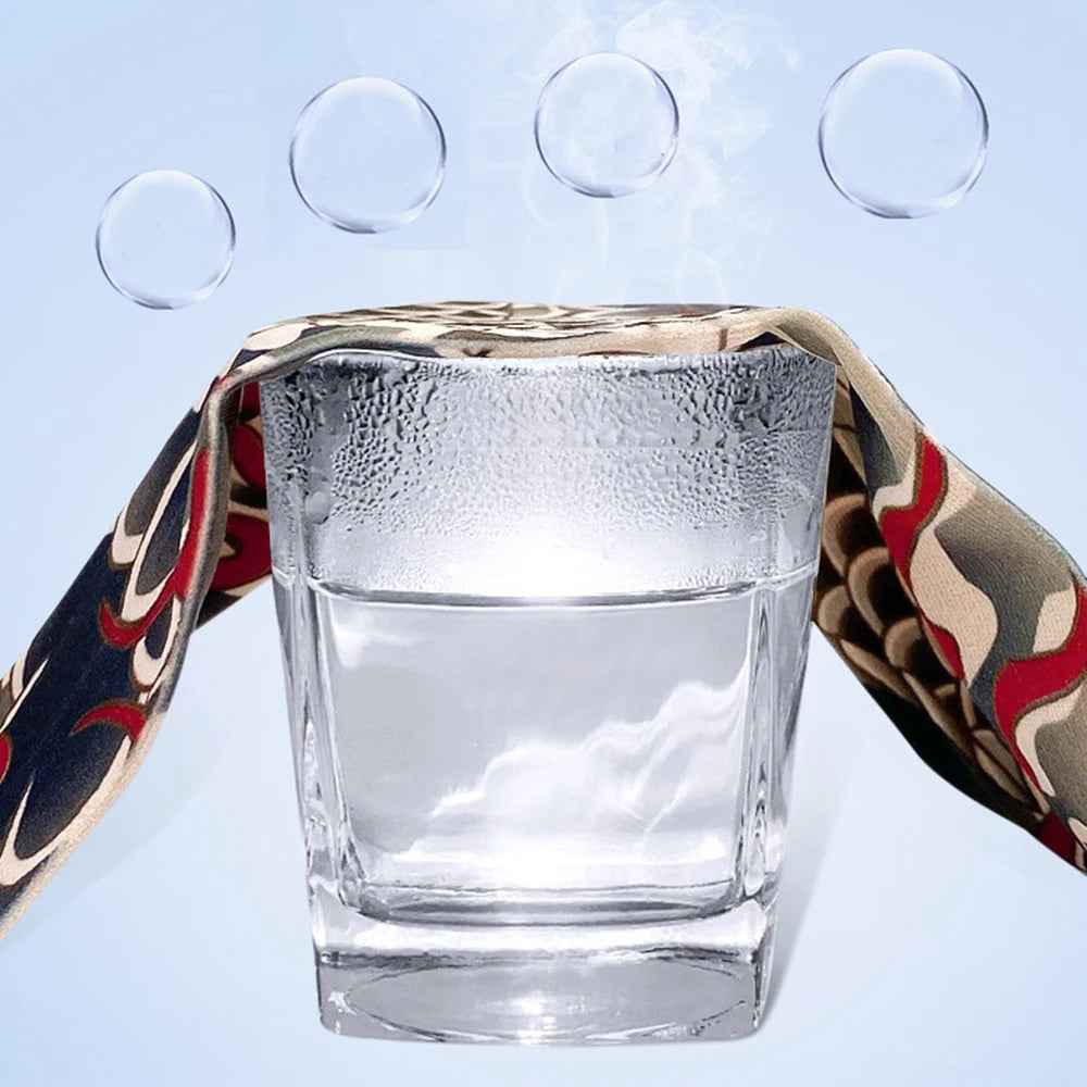 Clear glass tumbler filled with water, wrapped in a patterned fabric, with condensation droplets floating above.