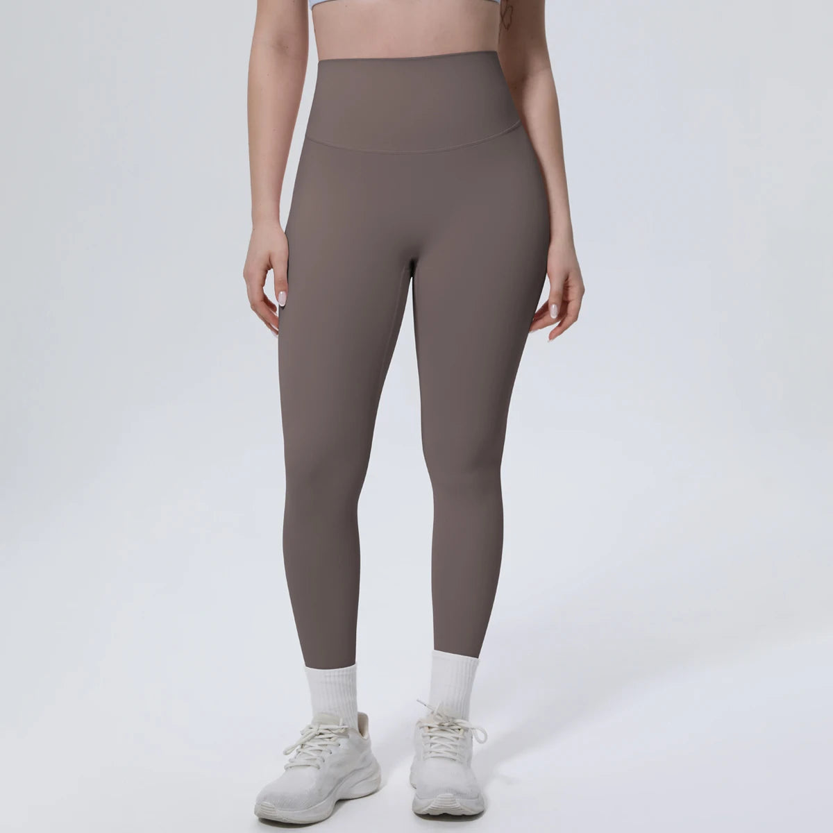 A model wearing high-waisted, full-length, dark gray quick-drying yoga and fitness leggings with white socks and light athlet