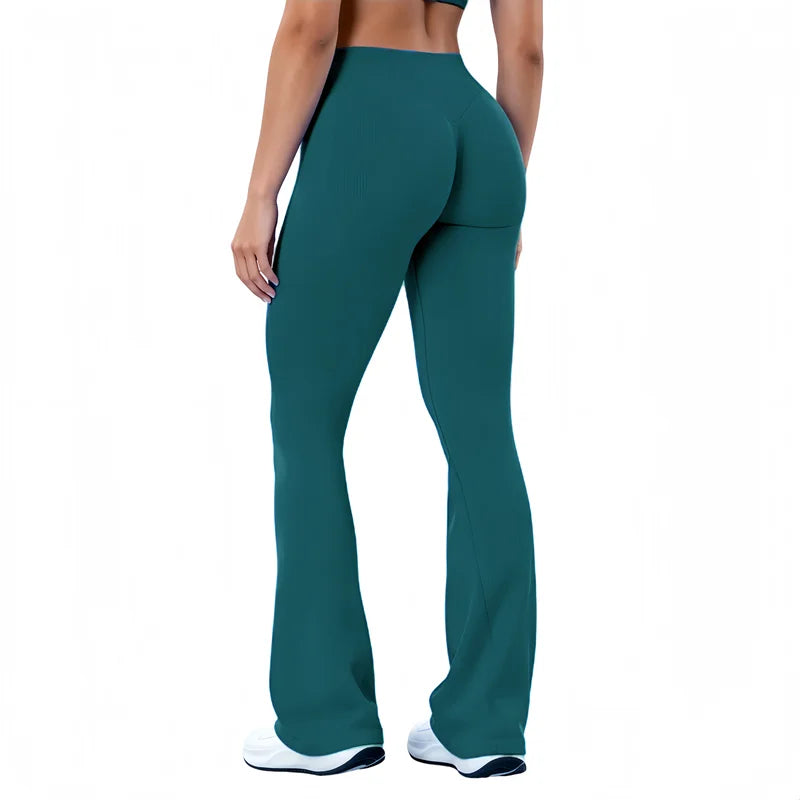 A person wearing dark teal seamless flared yoga leggings and white athletic shoes.