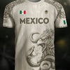 A white soccer jersey featuring an Aztec calendar design and the word MEXICO on the chest.