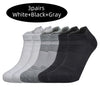 Three pairs of white, black, and gray performance running socks displayed side by side.
