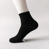 Black knitted men's mid-calf cotton socks shown on a model's ankle.