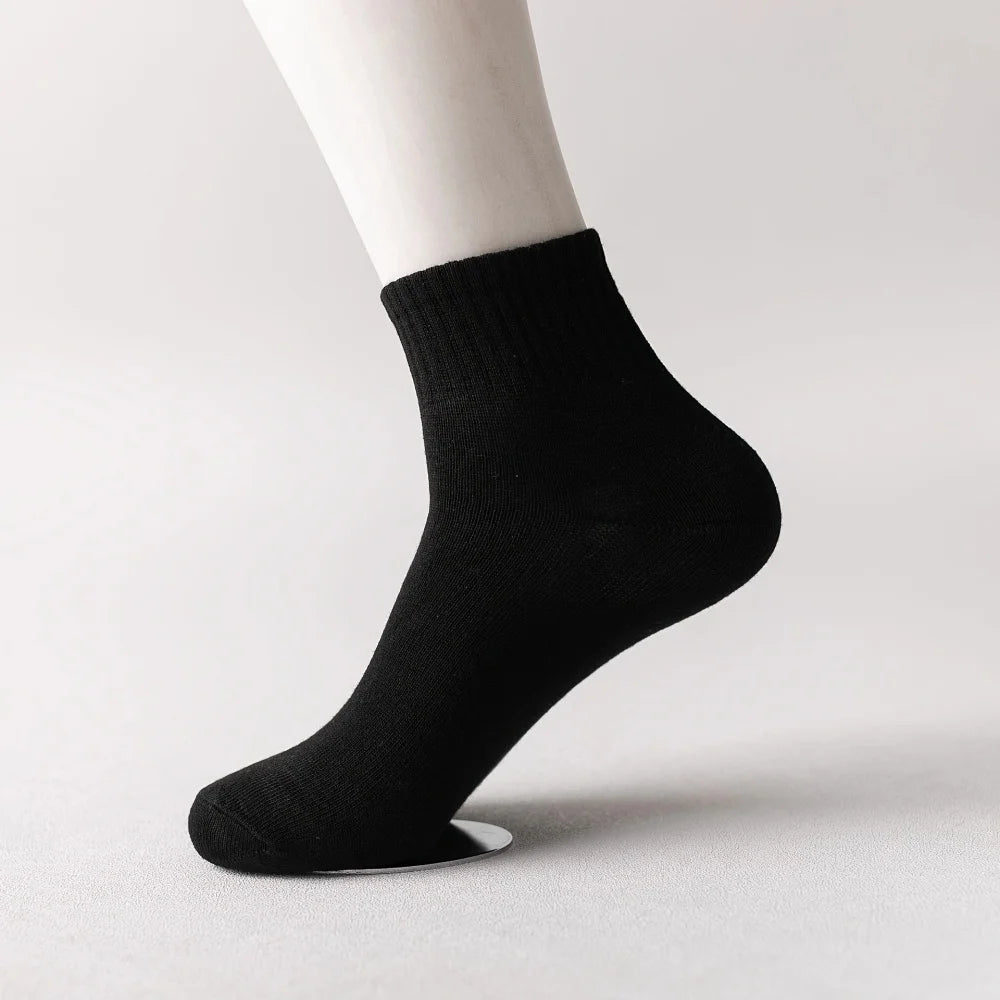 Black knitted men's mid-calf cotton socks shown on a model's ankle.