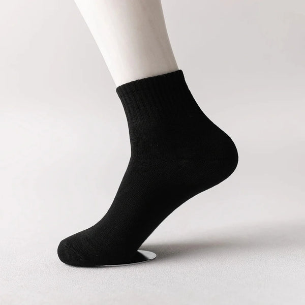 Black knitted men's mid-calf cotton socks shown on a model's ankle.
