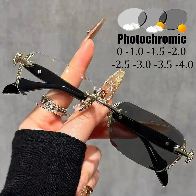 A hand holds a pair of black photochromic prescription glasses with gold accents, demonstrating light tinting capabilities.
