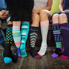 Four people sitting and wearing various colored knee-high compression socks.