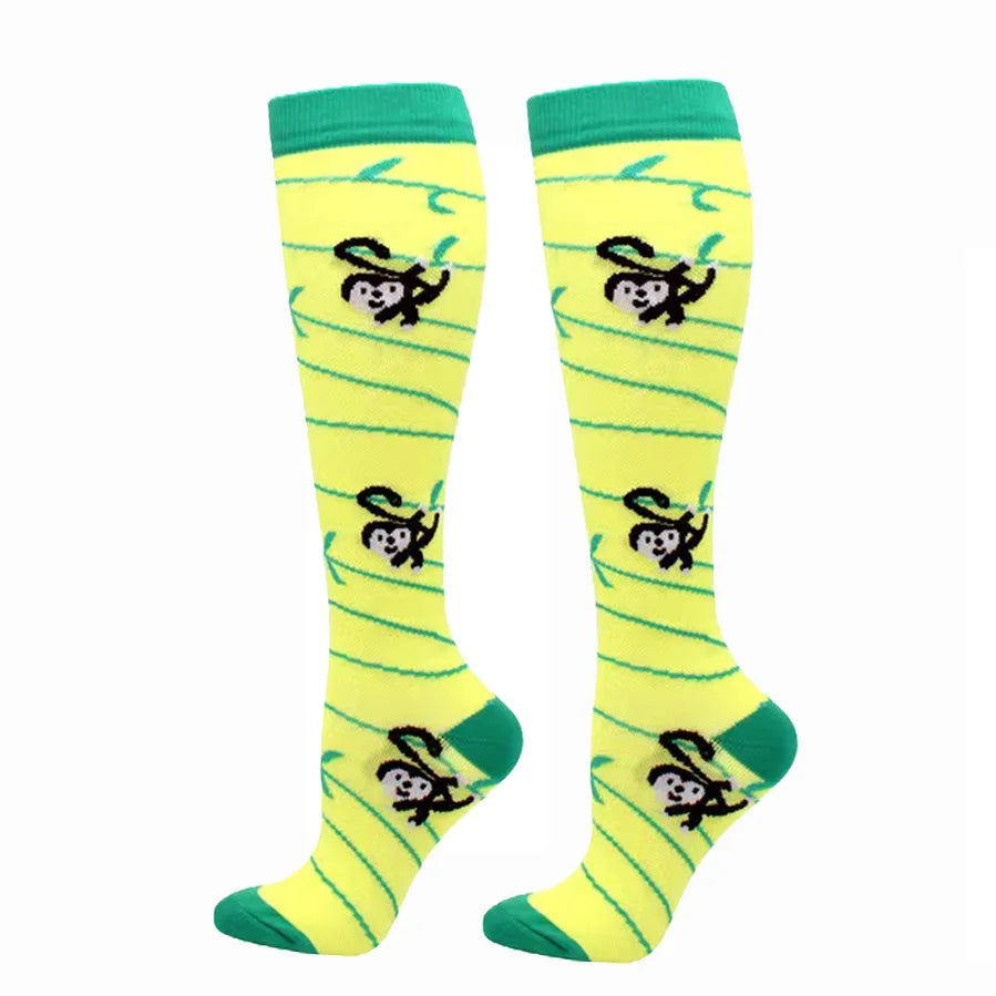 A pair of bright yellow compression elastic socks with green trim and black animal print designs.