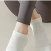 Gros plan de chaussettes de yoga blanches respirantes portées sur un pied, associées à un legging foncé.