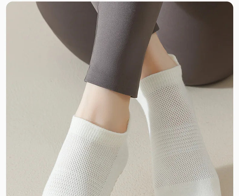Gros plan de chaussettes de yoga blanches respirantes portées sur un pied, associées à un legging foncé.