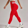 Eine Frau in roten, hochtaillierten, nahtlosen Yoga-Leggings und einem weißen Crop-Top posiert.