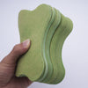 A hand holds a stack of light green self-heating lumbar spine patches.