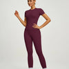 Model trägt ein sportliches Yoga-Set in tiefem Pflaumenton, bestehend aus langärmeligem Oberteil und Leggings.