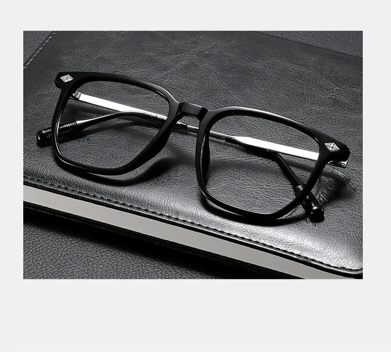 A pair of black retro anti-blue light glasses resting on a dark leather book.