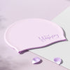 Gorro de natación de silicona rosa con la palabra Feliz, sobre un fondo claro.