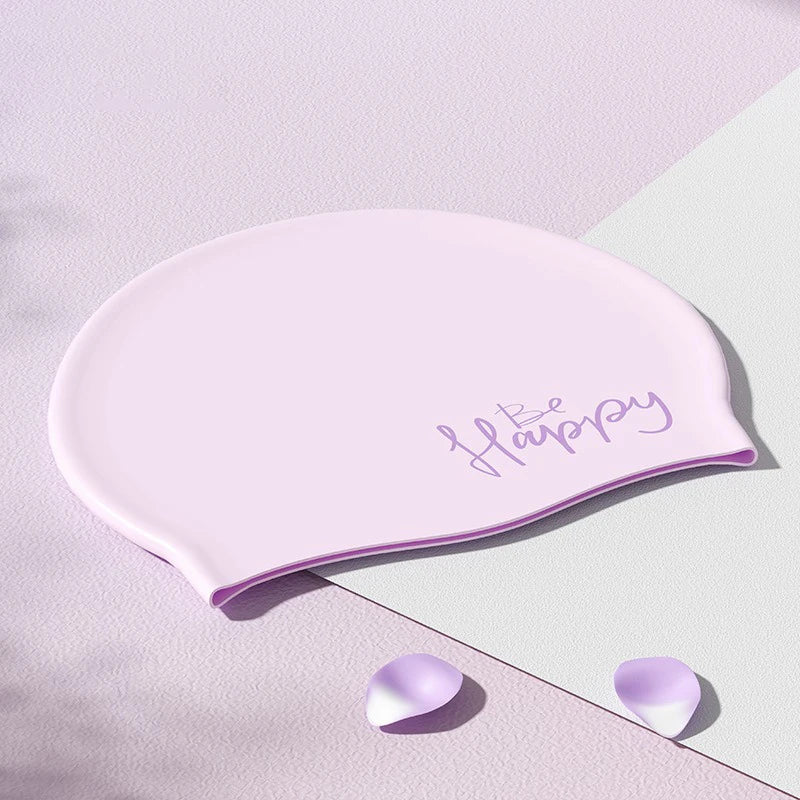 Gorro de natación de silicona rosa con la palabra Feliz, sobre un fondo claro.