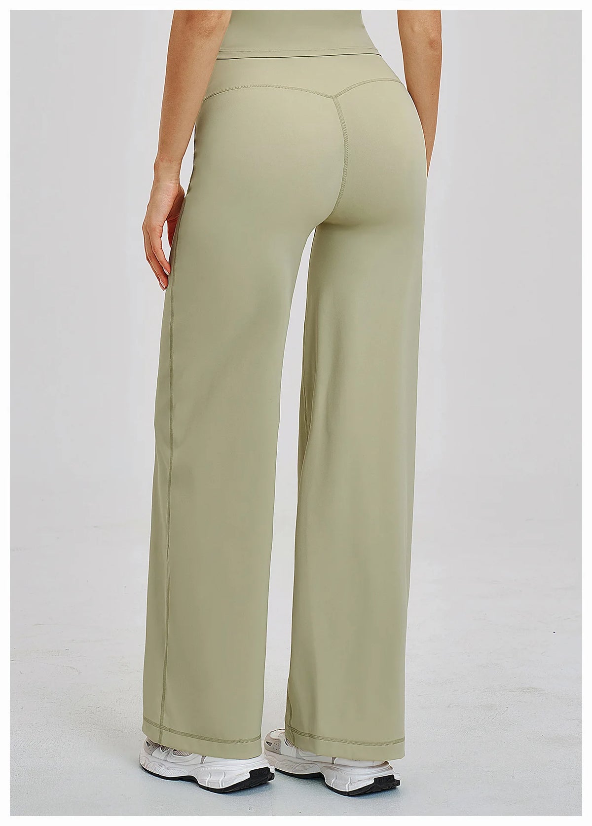 A woman wearing light olive green high-waist flared yoga pants from the back view.