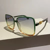 Retro two-tone gradient sunglasses with green and amber lenses resting on a white surface.